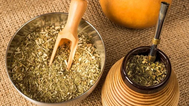 Yerba Mate leaves with traditional gourd and straw, energizing herbal tea extract.